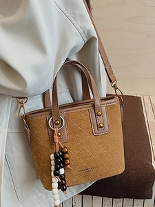 Sac seau en daim marron avec surpiqûres matelassées et charms perlés sur la poignée
