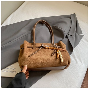 Dettaglio della borsa tote in pelle scamosciata marrone con perle di legno boho
