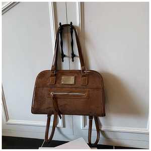 Detail shot of brown suede tote bag featuring leather trim and long fringe zipper pull