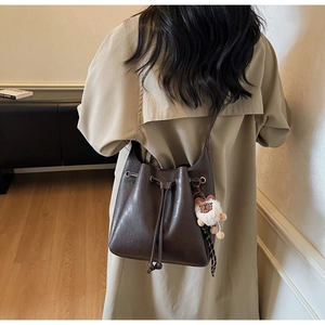 Close-up of a retro brown bucket bag featuring a drawstring closure and cute bear charm