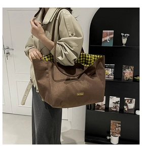 Detail of minimalist brown tote bag with contrast yellow plaid lining and dual shoulder straps
