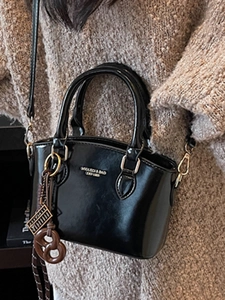 Glossy black crossbody bag for women with gold logo lettering and round bag charm
