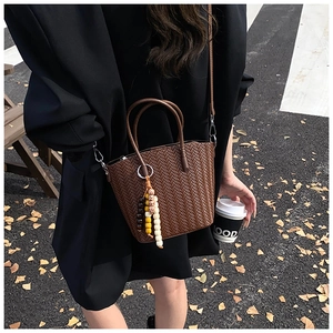 Brown woven texture bucket bag shown in a stylish street style urban commute setting
