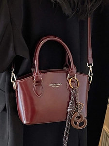 Polished burgundy shoulder bag with dual handles and woven charm for women's fashion