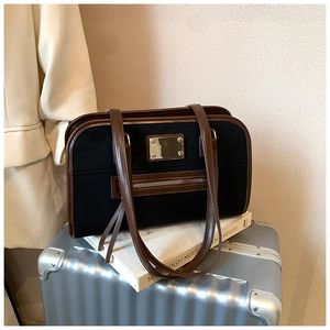 Detail of vintage tote bag with black suede texture and brown leather straps on luggage