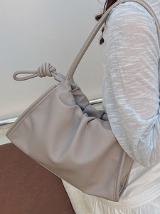 Elegant pleated shoulder bag in soft beige leather with knotted strap and minimalist design