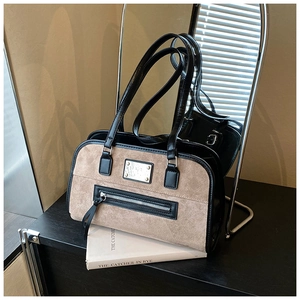 Close-up of vintage brown suede and black leather shoulder bag with metal logo detail