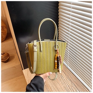 Close-up of woven leather texture on green crossbody bucket bag with wooden bead detail