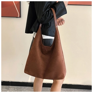 Detailed close-up of a brown matte faux suede tote bag with minimalist shoulder strap