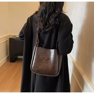 Detail showing the retro brown leather bucket bag with metal buckle on a black blazer