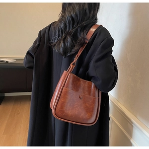 Close-up of vintage brown leather bucket bag showing oil-wax texture and snap pocket detail