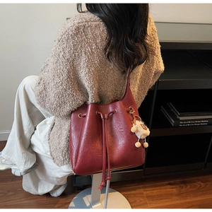 Detail of burgundy bucket bag with drawstring closure and cute white sheep charm