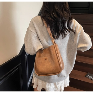Brown vintage faux leather hobo shoulder bag shown on a model on a wooden staircase