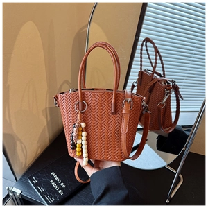 Macro detail of brown woven leather bucket bag with braided texture and colorful bead charm