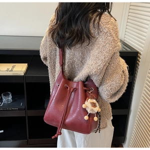 Detail of vintage red drawstring bucket bag with a cute plush charm on female model