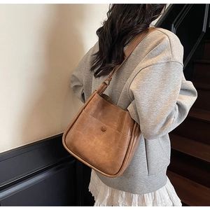 Detail of the vintage brown shoulder bag with a functional front pocket and smooth PU leather