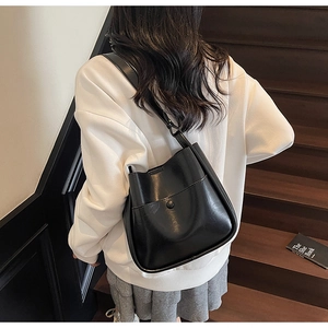 Detailed side view of high-capacity black leather bucket bag worn on a shoulder