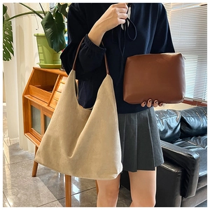 Beige suede tote bag and brown zip pouch set shown in a cozy indoor lifestyle scene