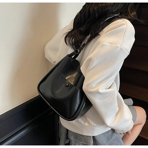 Detail showing the glossy black bucket bag with button pocket on a model side view