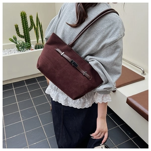 Dettaglio della borsa tote in pelle scamosciata marrone scuro con cinturino in pelle su modella
