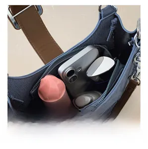 Détail de la capacité intérieure du sac en denim bleu avec téléphone et accessoires