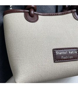 Macro detail of beige woven fabric texture with brown leather logo patch on a bucket bag