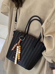 Black woven shoulder bag with beaded charm and herringbone pattern for daily fashion