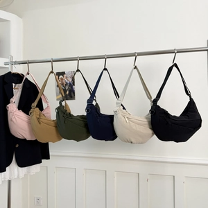 Array of minimalist nylon crescent bags in six vibrant colors displayed on a rack