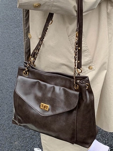 Deep brown oversized tote bag with gold chain strap and vintage twist lock for daily commute