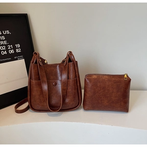 Detailed macro of vintage brown leather bucket bag set with matching zippered clutch