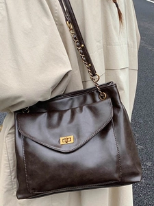 Brown PU leather tote bag with metal chain strap and turn-lock front pocket shown on model
