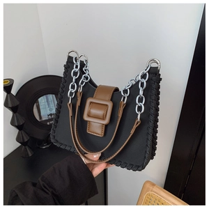 Détail d'un sac bandoulière noir tissé avec lanière en cuir marron et chaîne argentée