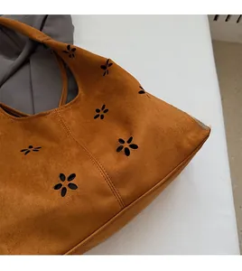 Gros plan détaillé d'un sac cabas en daim marron avec motifs floraux ajourés au laser