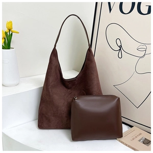 Detail of dark brown faux suede Hobo bag and small matte leather pouch on minimalist shelf