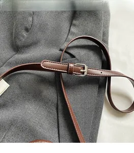 Close-up of adjustable brown leather strap with silver buckle on a woven bucket bag