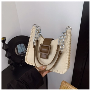 Détail du sac en toile beige et cuir marron cousu main avec bandoulière chaîne argentée