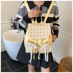 Dettaglio dello zaino giallo con fiocchi in pizzo bianco e tasche con coulisse