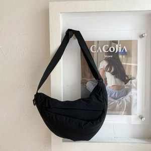 Detail view of black quilted crossbody bag with adjustable strap and double zipper finish