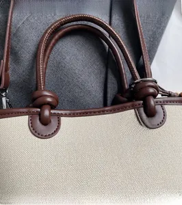 Detail of canvas bucket bag with brown leather trim and knotted handle design