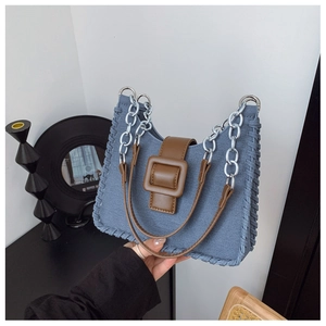 Détail du sac bandoulière en jean bleu avec boucle en cuir marron et bordure tressée