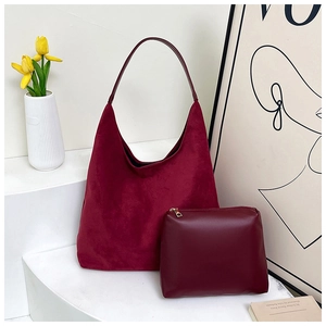 Detail of burgundy suede tote bag and matching leather pouch on a minimalist stand