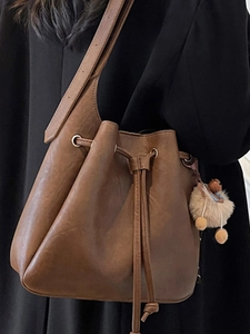 Retro brown drawstring bucket bag in soft leather with plush pompom for women