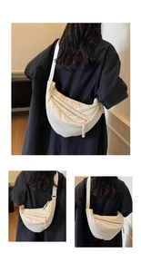 Detail of a creamy white pleated hobo bag with textured fabric and adjustable strap