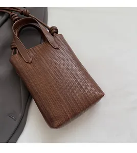 Detailed view of dark brown woven texture on a minimalist vertical mini crossbody phone bag
