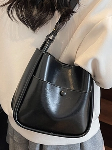 Minimalist black glossy bucket shoulder bag with sleek synthetic leather and round snap pocket