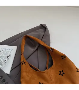 Détails des motifs floraux découpés au laser sur un sac cabas en suédine marron