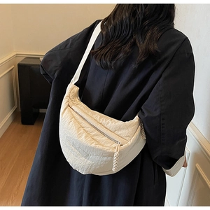 Detail of cream crescent crossbody bag with pleated texture and woven rope zipper