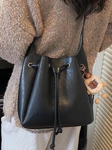 Minimalist black bucket bag with drawstring closure and cute plush charm detail