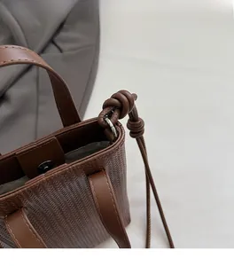 Close-up of woven texture brown tote with magnetic clasp and leather knot detail