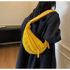 Detail of a bright yellow crescent nylon bag featuring unique crinkle texture and woven zipper